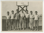 Young men and boys standing in front of basketball goal