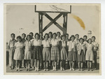 Young men and women standing in front of basketball goal