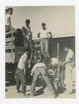 Seven men grouped around the back of truck