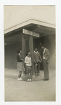 Two men and two women standing outside building under "school offices" sign